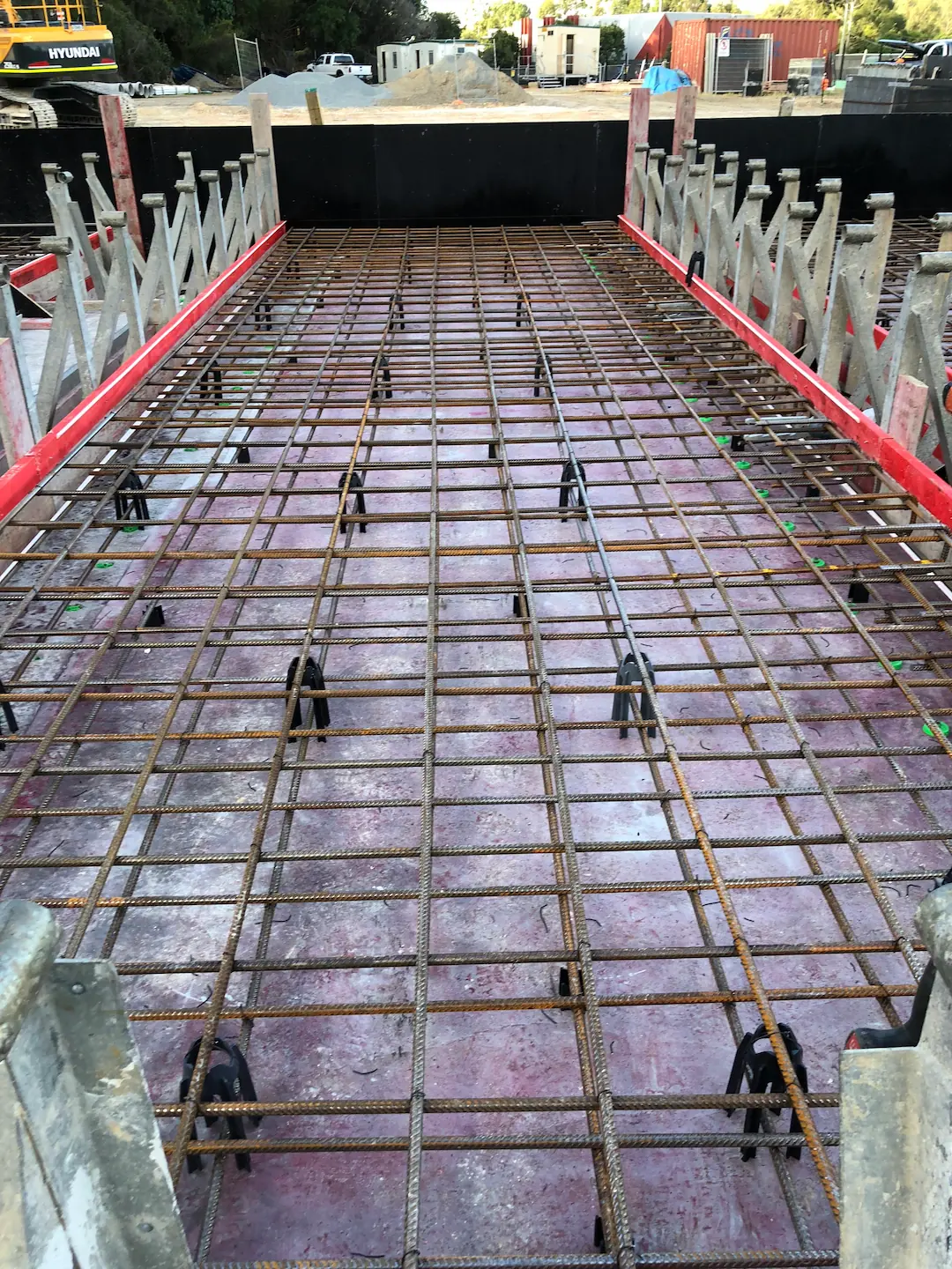 Advanced stage of concreting with reinforcement bars meticulously arranged over a waterproofing membrane, ready for concrete pour.