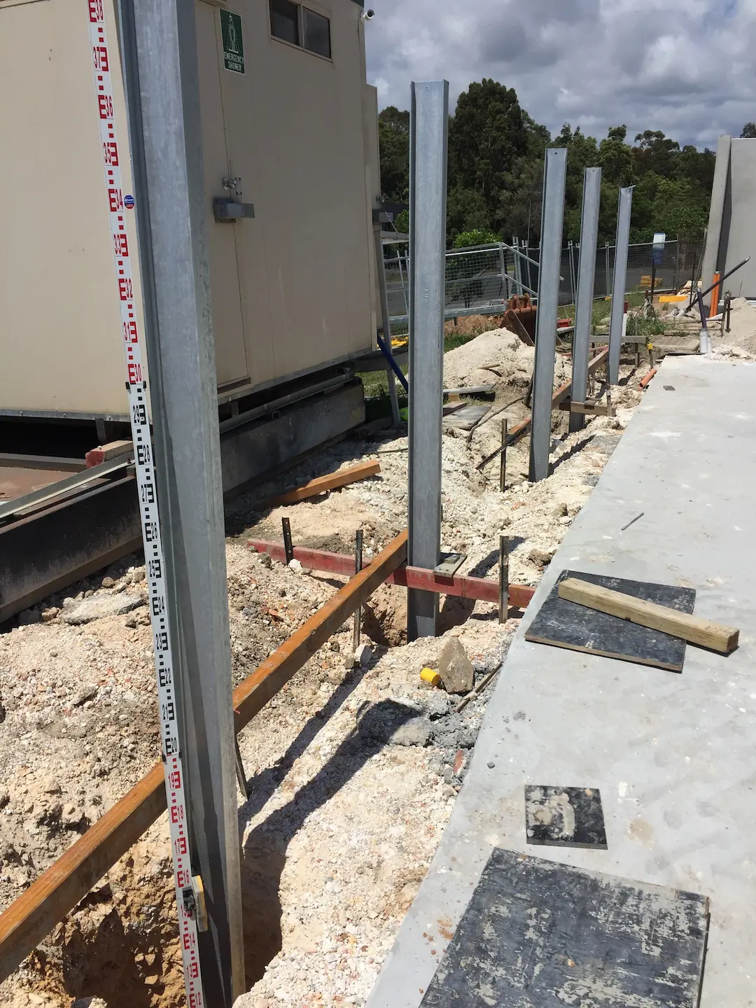 Detailed view of the measurement and alignment process in concreting with focus on a metal ruler and spacing elements on a work site.