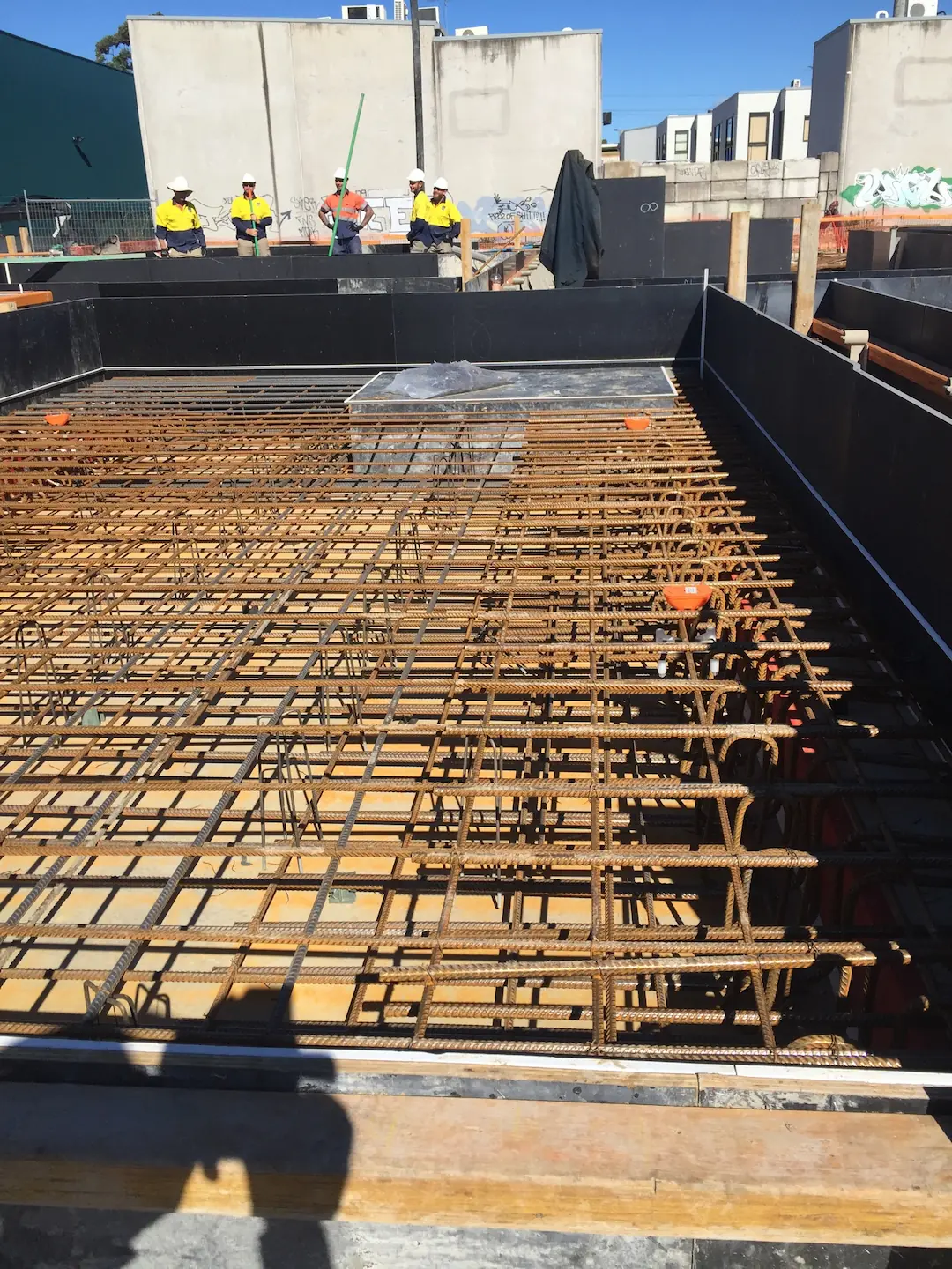 Construction workers in safety gear overseeing a large area with densely arranged rebar at the Kirawee commercial concreting project.